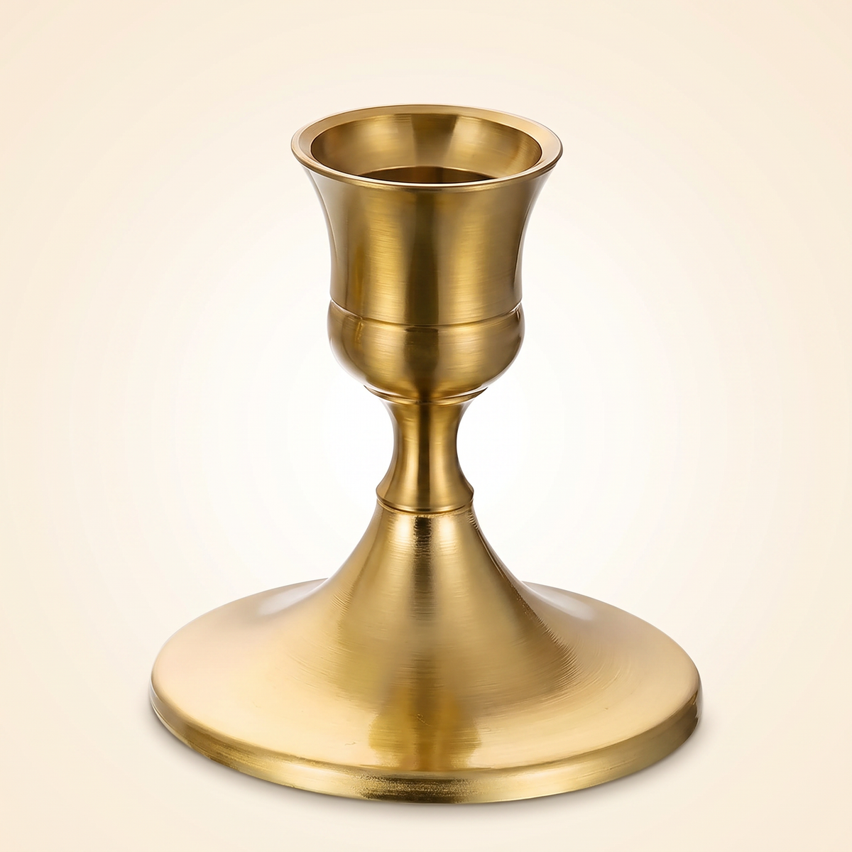 Single brass gold taper candlestick holder on a clean studio background