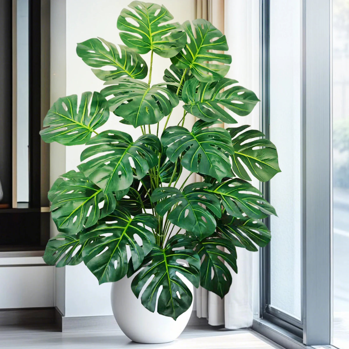 Artificial monstera Blanka in dark green by a large window