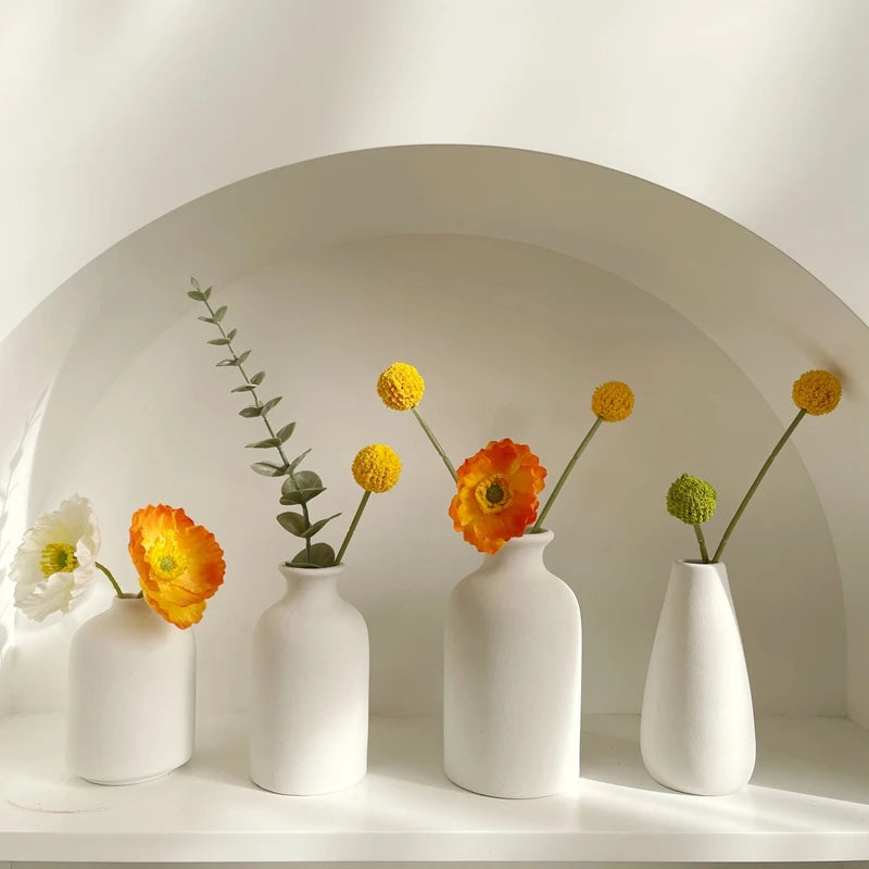 White ceramic bud vases with poppies and eucalyptus in an arched alcove