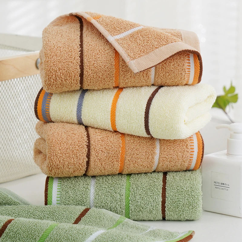 Stack of striped cotton hand towels Olga in sage, cream and camel next to a basket