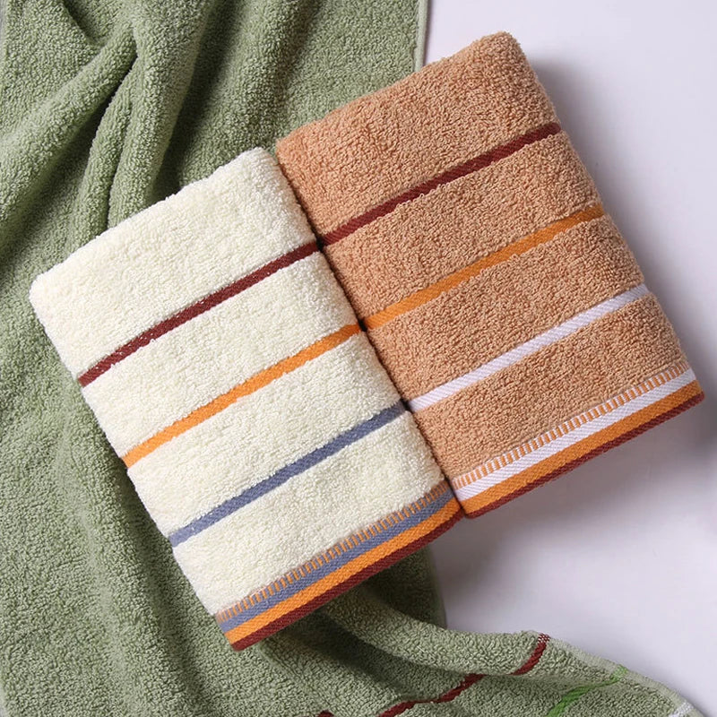 Cream and camel striped hand towels folded on a sage green towel