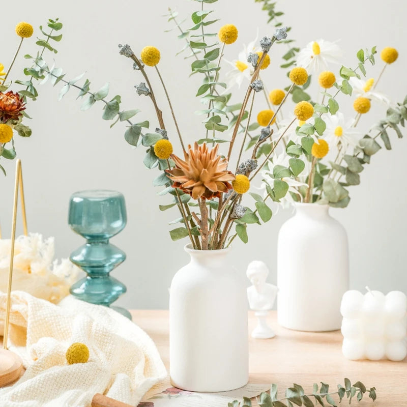 White ceramic vases with eucalyptus and dried flowers on a table