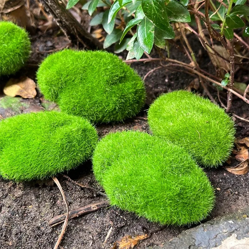 Green faux moss rocks of different sizes laid on dark soil