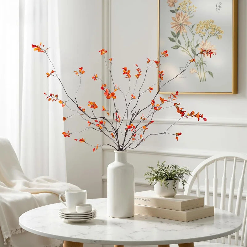 Red-orange autumn branches in a white vase on a round table