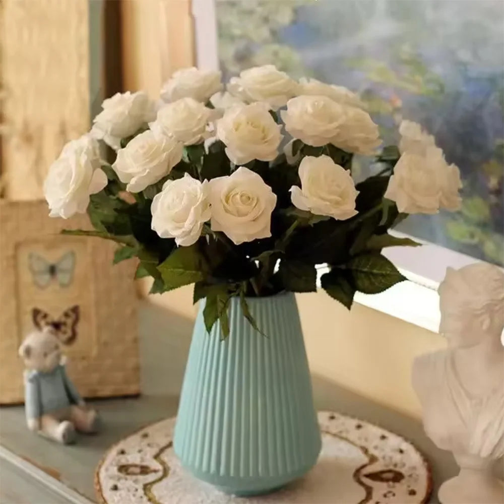 White roses in a ribbed vase on a window sill