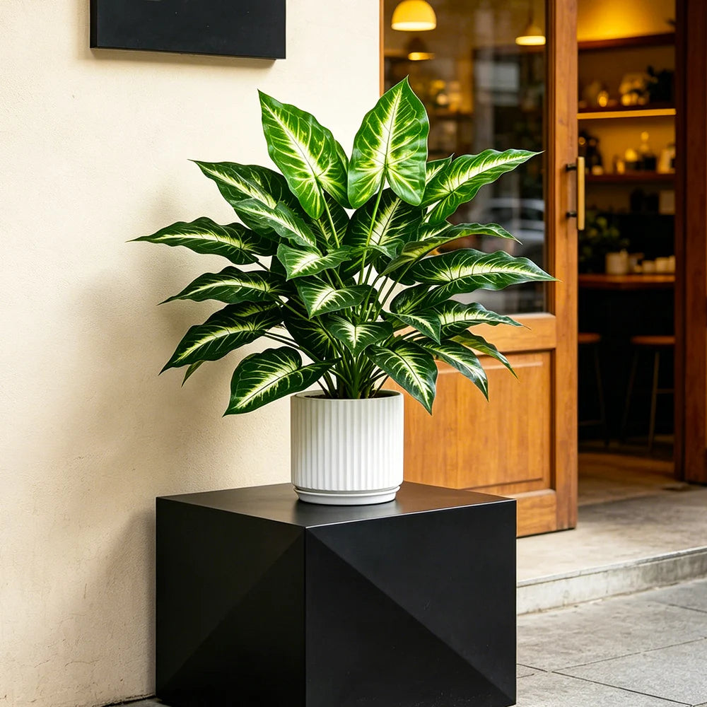 Small variegated faux leaf plant in a white pot on a dark stand