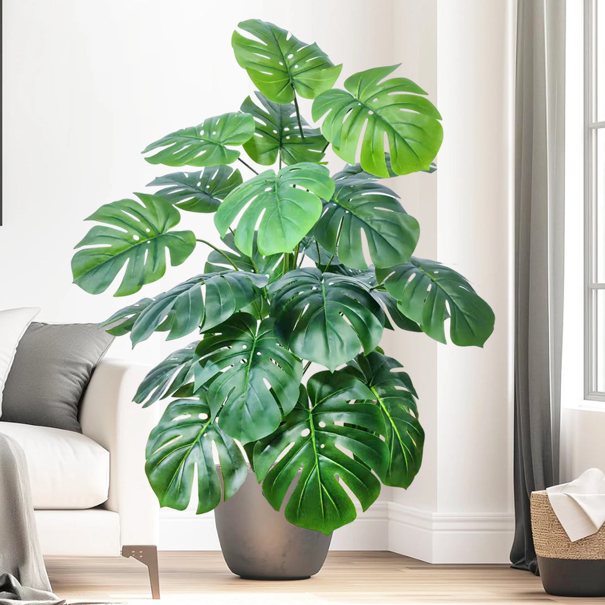 Artificial monstera Blanka in fresh green next to a sofa