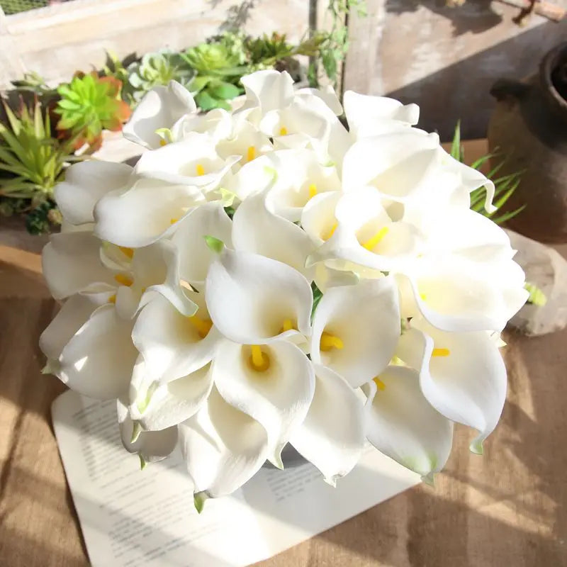 Bunch of white calla lilies on a wooden table