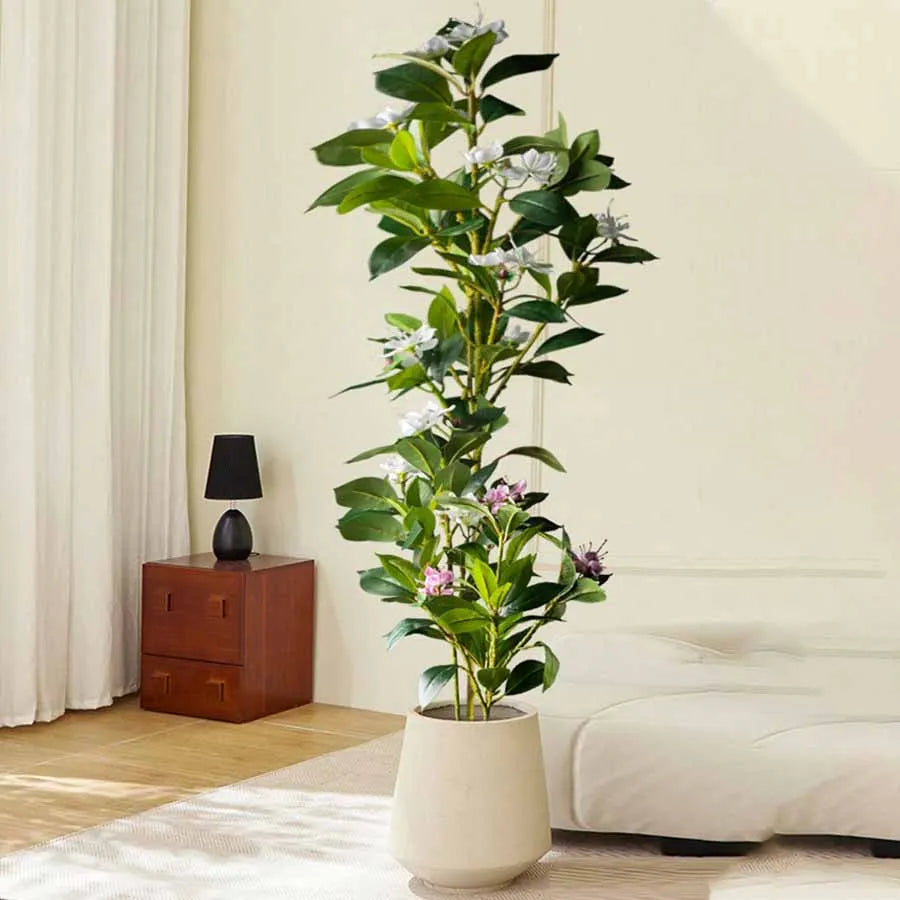 Faux flowering stem Denisa in a cream planter next to a sofa