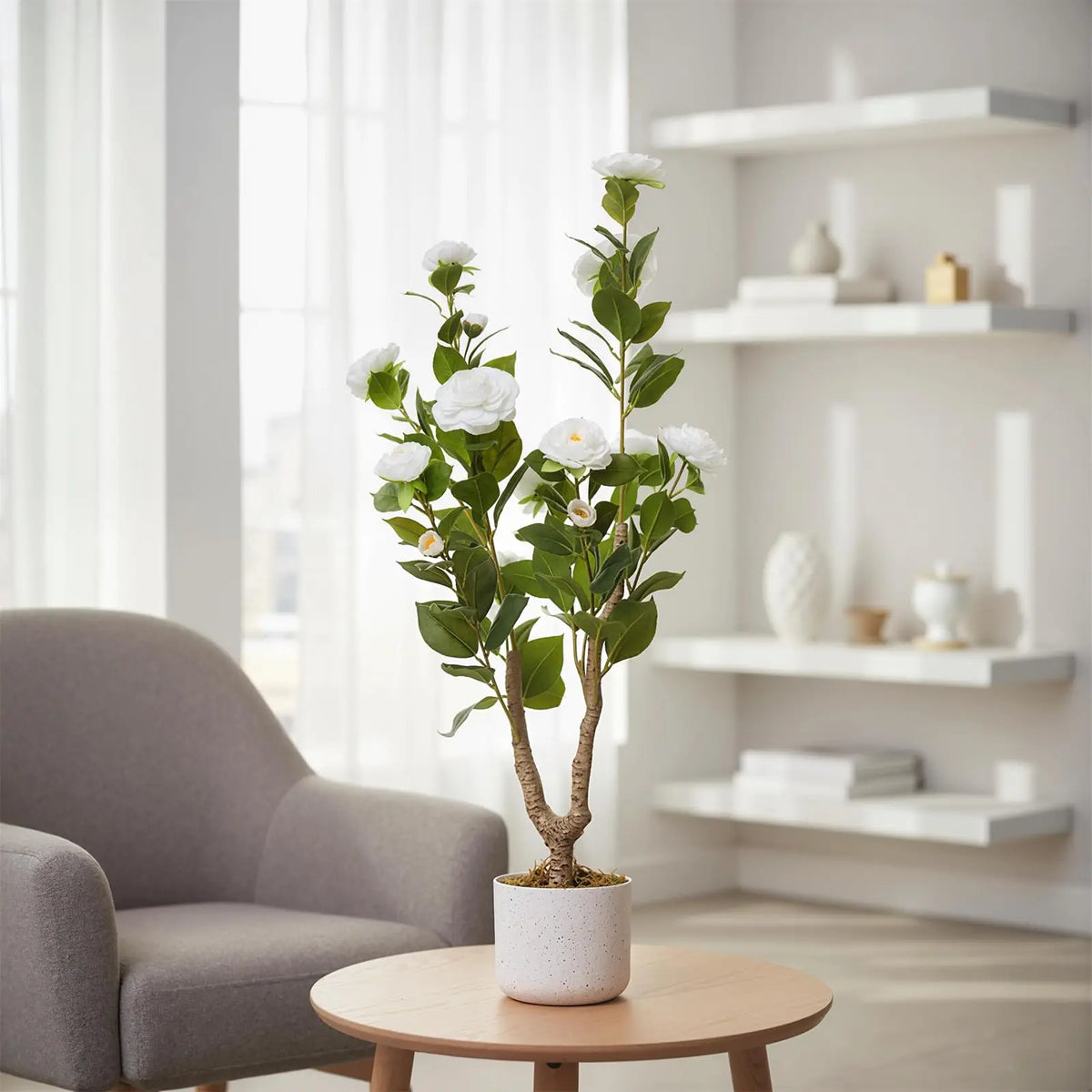 Faux camellia tree Etela with white flowers in a white planter on a side table