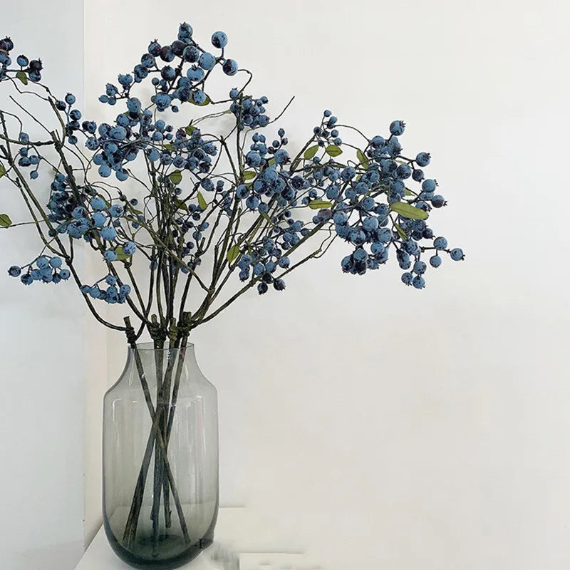 Dusty blue faux berry branch in a tall glass vase