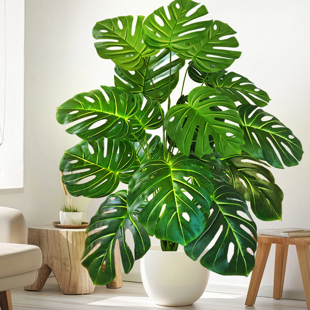 Artificial monstera Blanka in fresh green beside a wooden stool