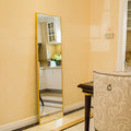 Standing Mirror Ivona with a slim gold frame in a warm room