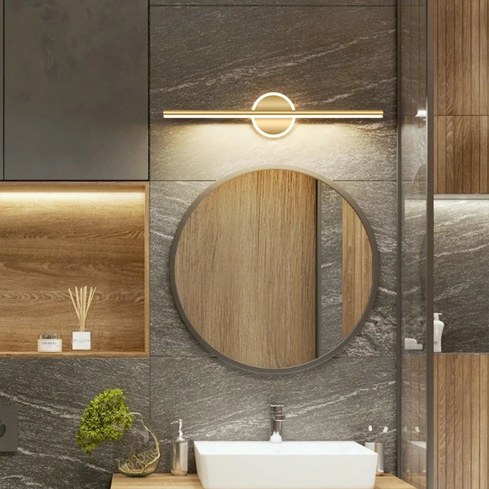 Vanity Light Erik in gold above a round mirror in a marble bathroom