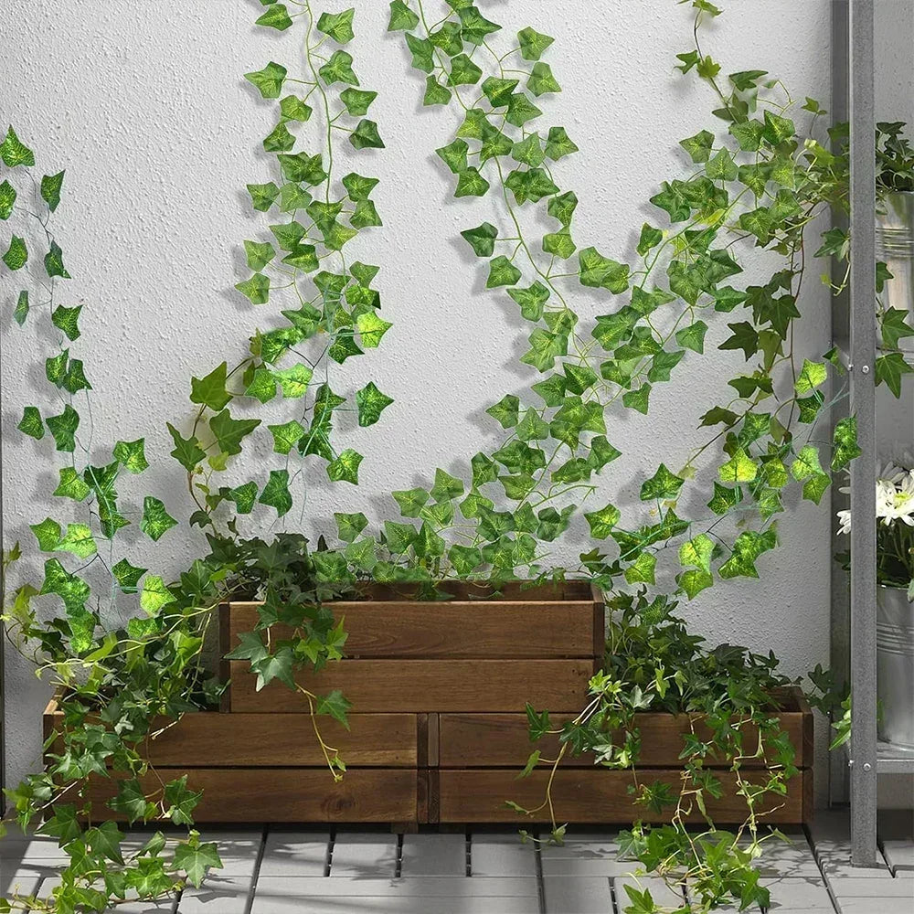 Faux ivy strands trailing from a wooden planter box against a white wall