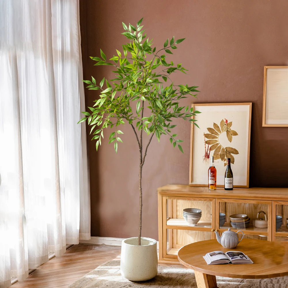 Faux nandina stem Elvíra in a white planter beside a wooden sideboard