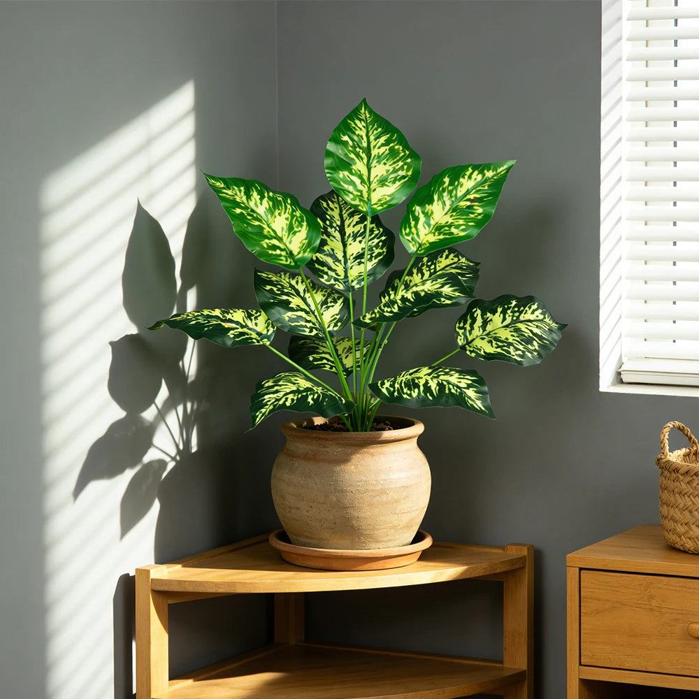 Speckled faux leaf plant in a clay pot on a wooden stand