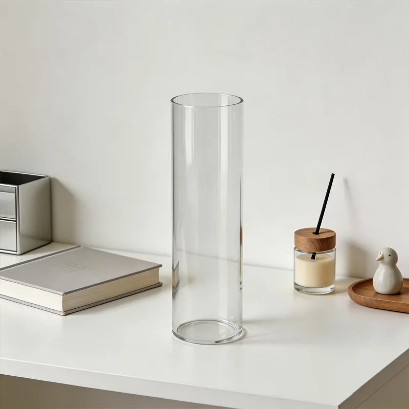 Empty clear acrylic cylinder vase on a white console table