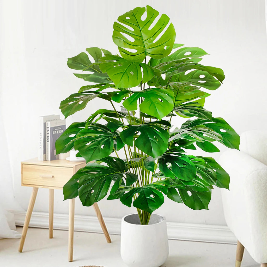 Artificial monstera Blanka in fresh green beside a side table