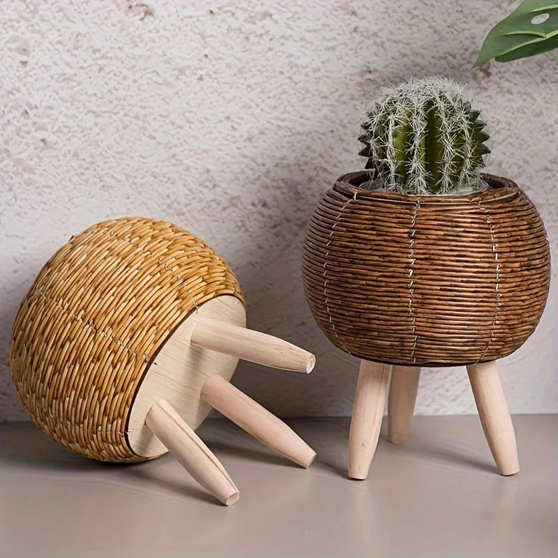 Round rattan ball planters on wooden legs with a cactus, one planter turned over to show the legs