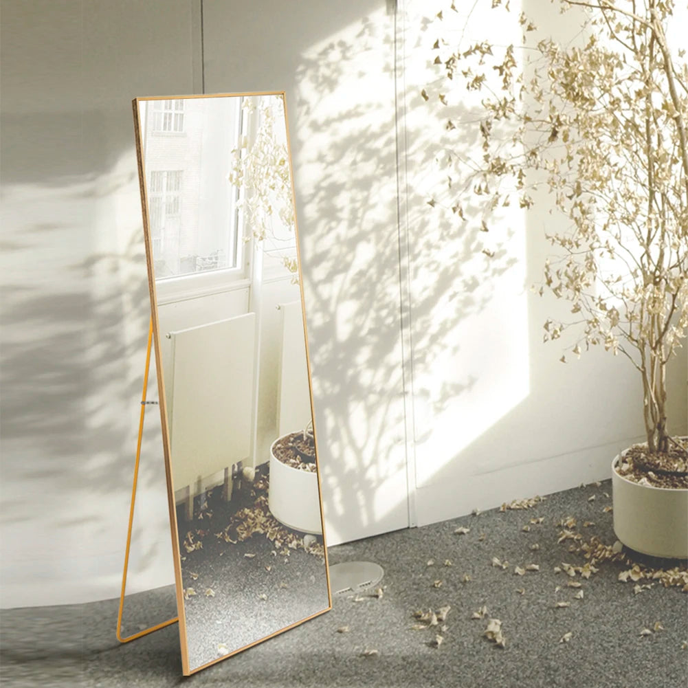 Standing Mirror Ivona in sunlight next to a large plant