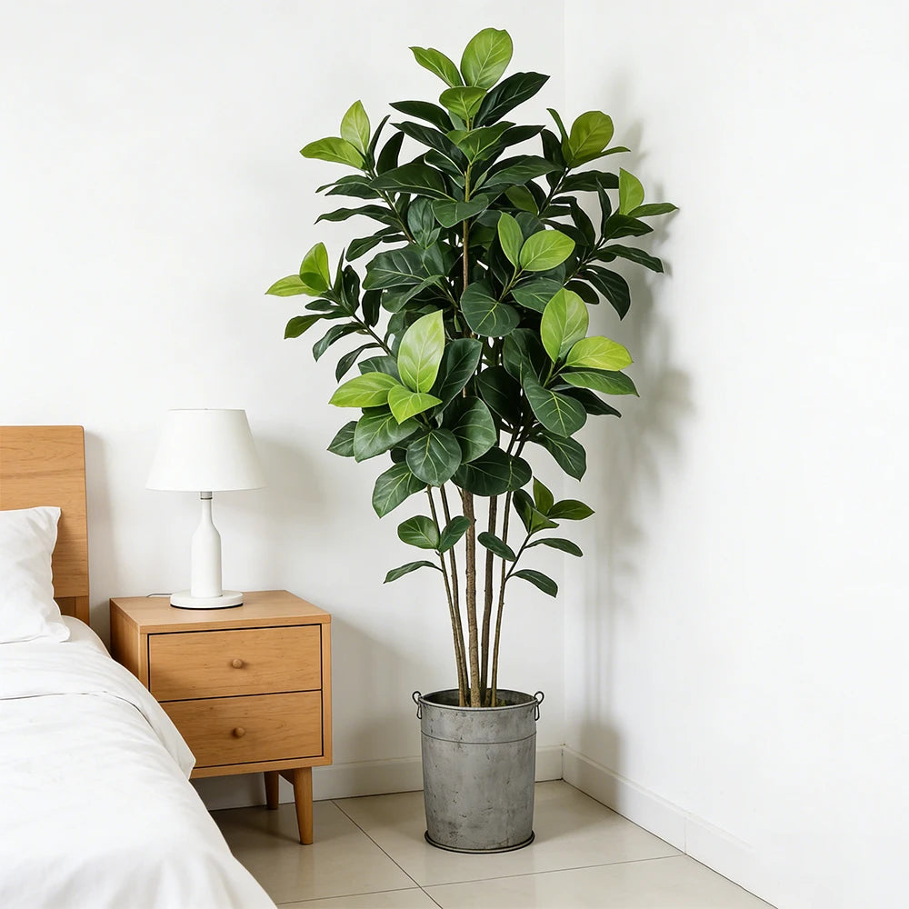 Tall faux ficus stem Brigita in a grey planter next to a bed
