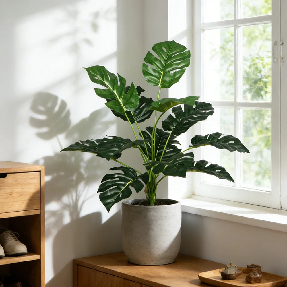 Monstera-leaf faux plant in a pot by a bright window