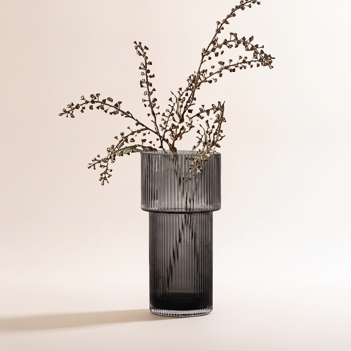 Gray Nora ribbed glass vase with a dried seed-pod branch, studio photo