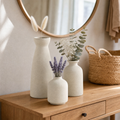 Set of three warm beige matte ceramic vases grouped on an oak console table with dried lavender and eucalyptus