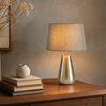 Desk Lamp Ondrej in champagne-silver finish with gray fabric drum shade, styled on a walnut desk