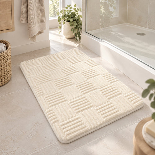 Bath Mat Silvia in cream with a raised woven pattern on a bathroom floor in front of the shower